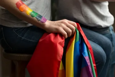 Primer plano de pareja joven lesbiana sosteniendo la bandera lbgt en la mano