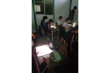 Estudiantes de bachillerato de la I.E. Pío XII, de Neira, recurren a lámparas de celulares por falta de energía y luz natural. 