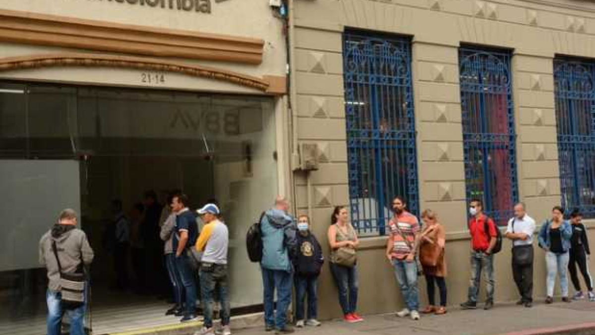 Gente hace fila afuera de una oficina de Bancolombia en el centro de Manizales.