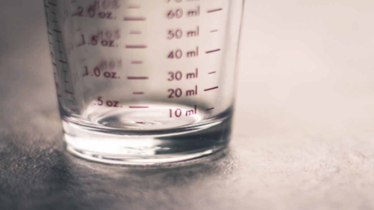 Parte baja de un vaso medidor transparente en una mesa gris.