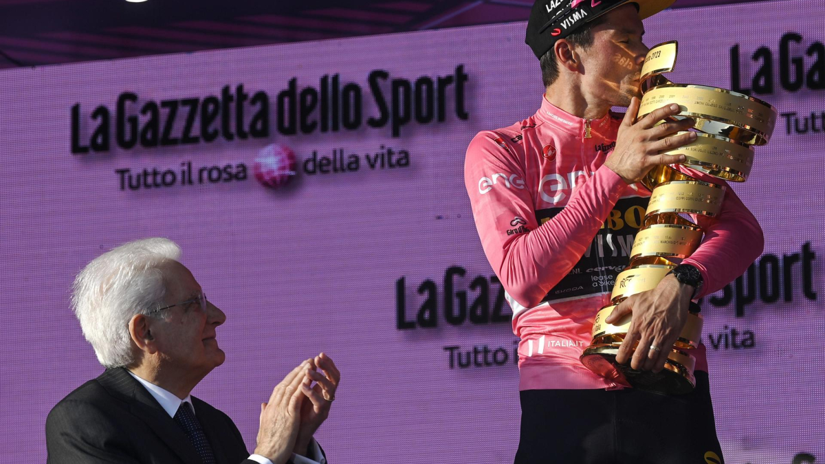 El nuevo ganador del Giro de Italia, el esloveno Primoz Roglic (derecha), besa el trofeo de la competencia, que recibió del presidente italiano, Sergio Mattarella.