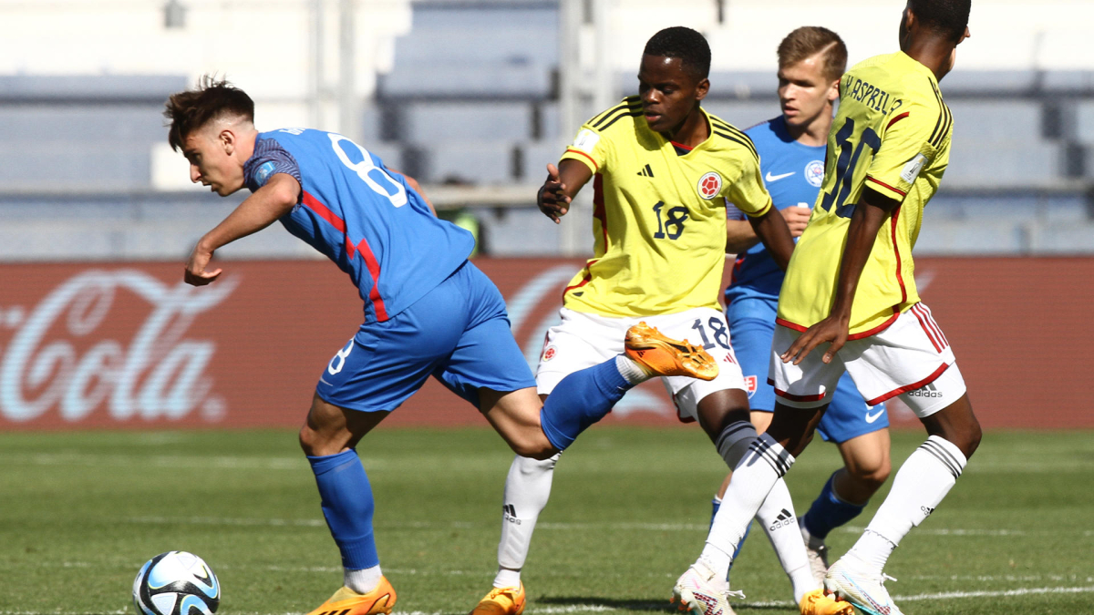 El colombiano Jhojan Torres (centro) un balón con Artur Gajdoš de Eslovaquia.