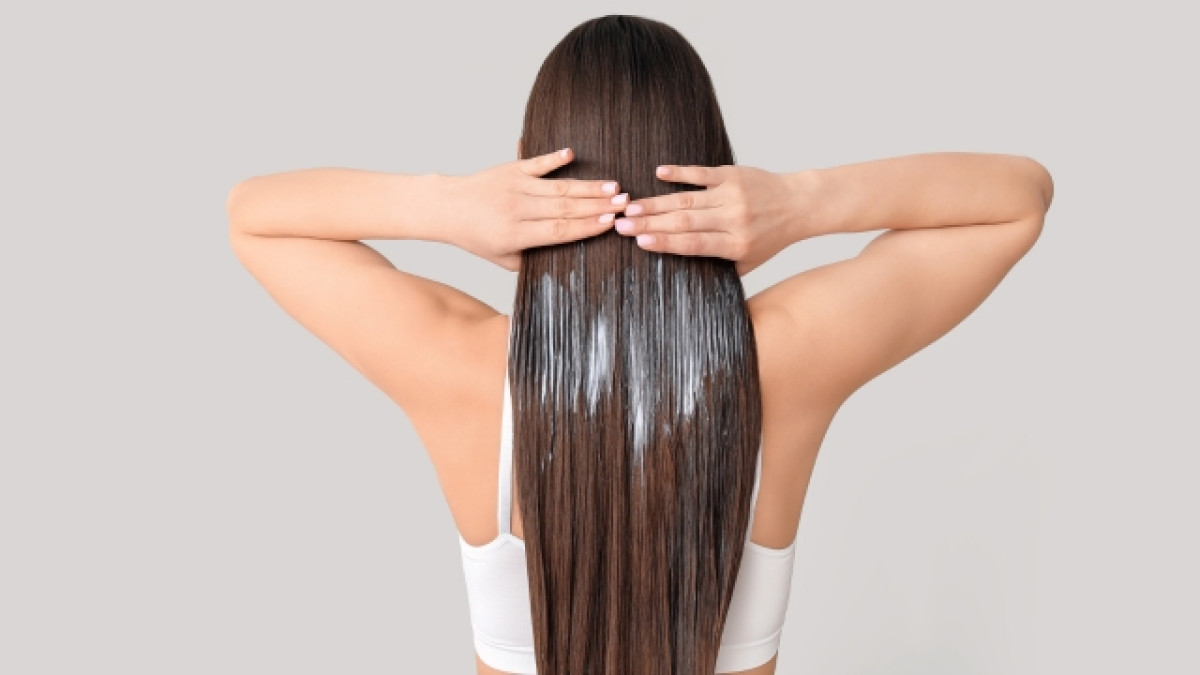 Mujer de espalda se pasa las manos por su cabello castaño
