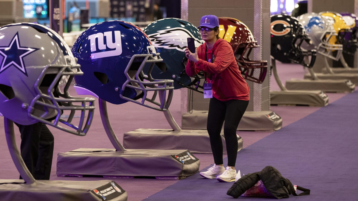 Una mujer toma una fotografía de cascos de fútbol de gran tamaño en la experiencia del Super Bowl en el Centro de Convenciones Mandalay Bay South en Las Vegas, Nevada, EE.UU.