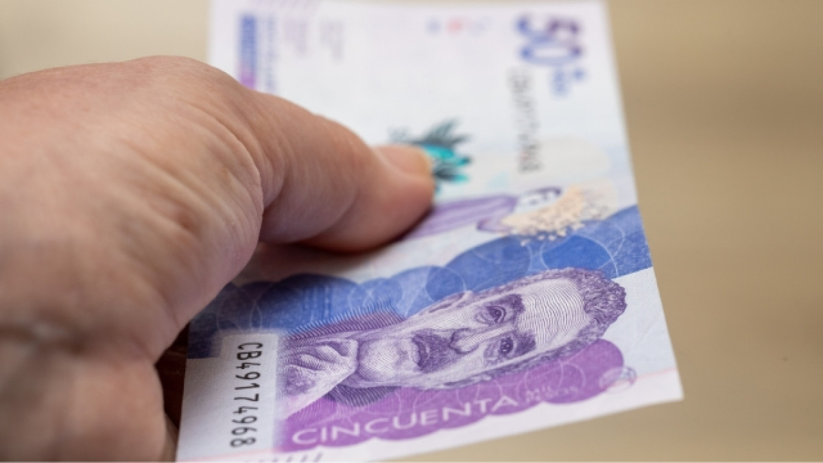 Mano sosteniendo un billete de 50 mil pesos colombianos.