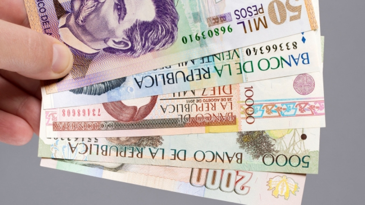Mano sosteniendo pesos colombianos