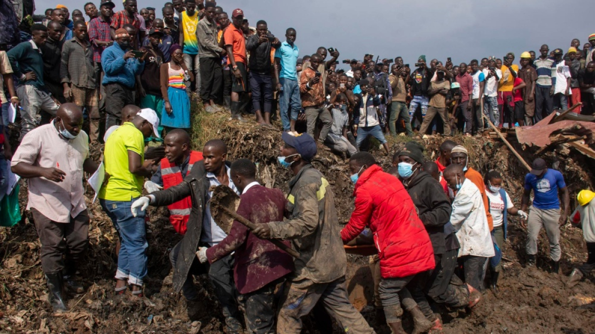 Varias personas llevan a un superviviente a un lugar seguro durante las labores de rescate después de que un deslizamiento de tierra sepultara casas en un vertedero en el distrito de Kiteezi, Kampala, Uganda,