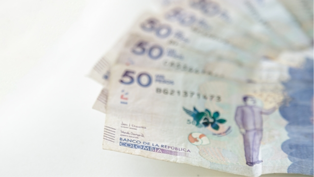 Mano sosteniendo billetes de 50 mil pesos colombianos
