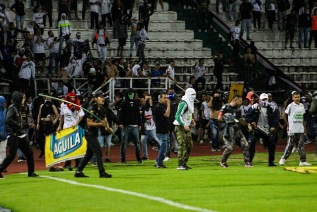 Hinchas se niegan a dejar la cancha y tratan de enfrentar al ESMAD, incluso un de ellos con el banderín del tiro de esquina.