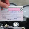 Como-saber-si-mi-soat-esta-vigente  Persona sosteniendo un SOAT frente al tablero de una moto.