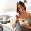 Una-mujer-embarazada-puede-comer-picante Mujer embarazada comiendo de un bowl en una cocina.
