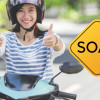 Como-saber-si-mi-moto-tiene-soat Mujer en moto al lado de un aviso que dice "SOAT"