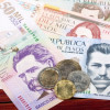 Como-calcular-los-intereses-de-las-cesantias Billetes y monedas de plata colombiana en una mesa de madera.