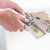Las-vacaciones-se-pagan-aparte-del-sueldo Manos sosteniendo billetes de pesos colombianos.