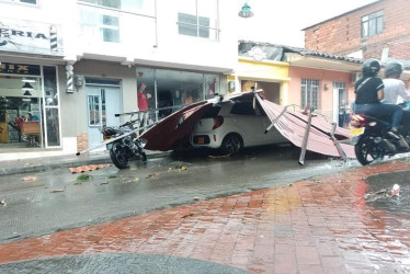 Un vehículo particular blanco quedó atrapado bajo unas láminas metálicas tras el vendaval.