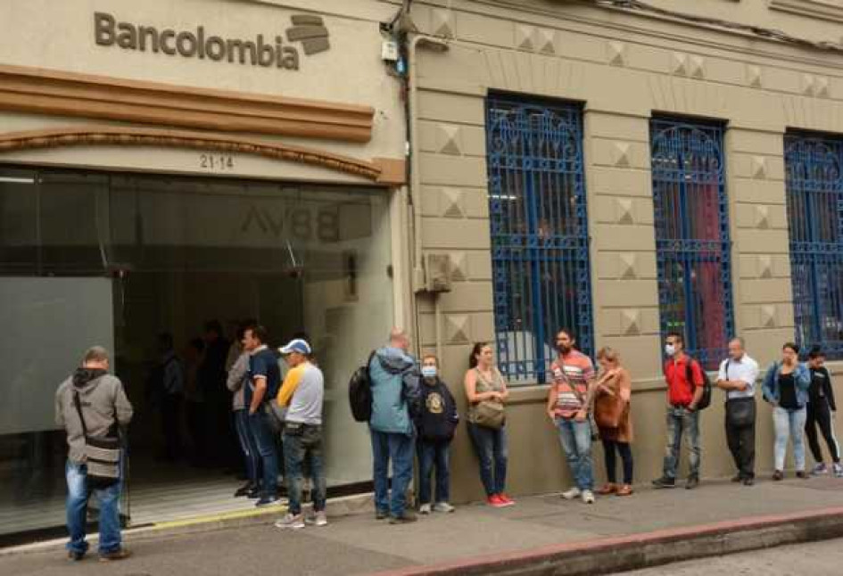 Cómo saber si soy beneficiario del Ingreso Solidario Gente hace fila afuera de una oficina de Bancolombia en el centro de Manizales.